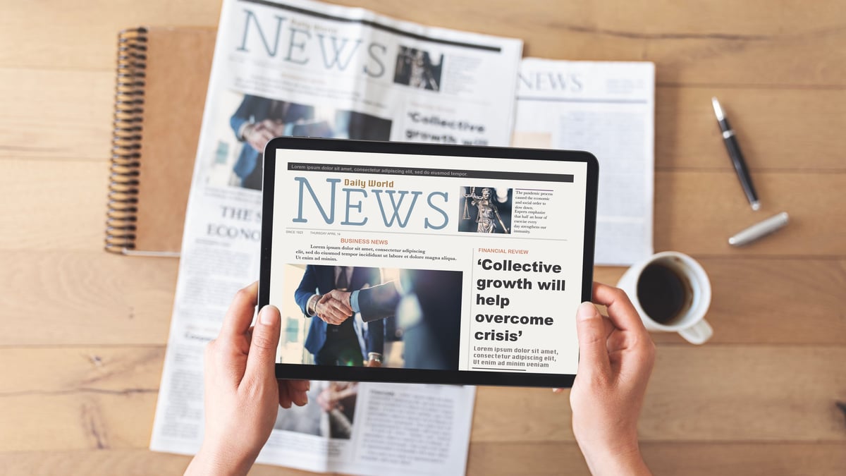 Reading newspaper with digital tablet representing Arabian Business's cross-platform reach across print and digital media in the Middle East
