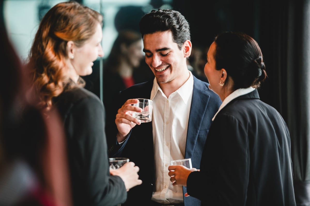 Business professionals gather after work for drinks and casual conversation, a relaxed office party moment showing teamwork and positive workplace culture