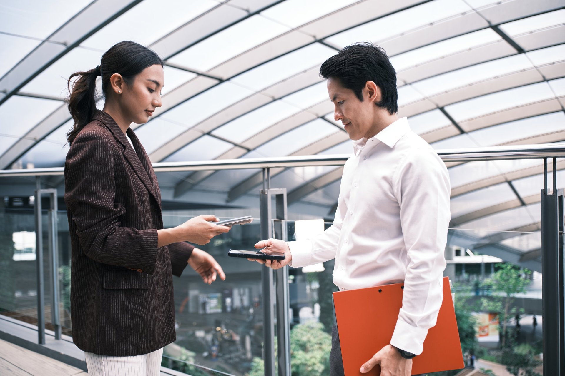 Two professionals exchanging contact details with an NFC tap card outdoors