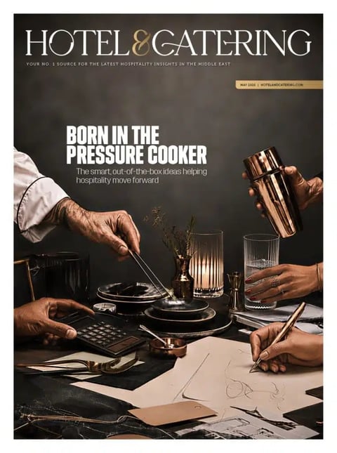 Hotel and Catering magazine cover featuring hands preparing food with pressure cooker and kitchen tools on a table