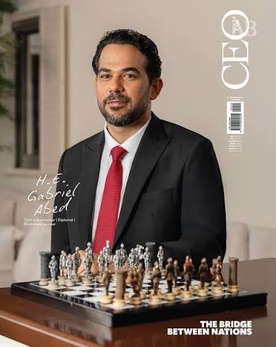 Man in black suit and red tie standing behind a chess board, CEO magazine cover