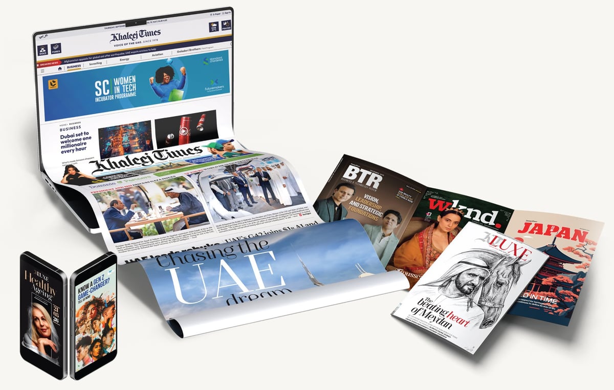 Collection of entertainment media items including laptop displaying website, magazines, printed materials, and DVD cases arranged on white background
